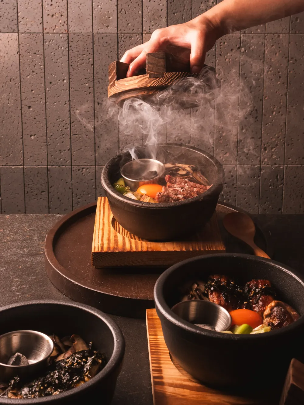 Steaming claypot dishes served on wooden boards