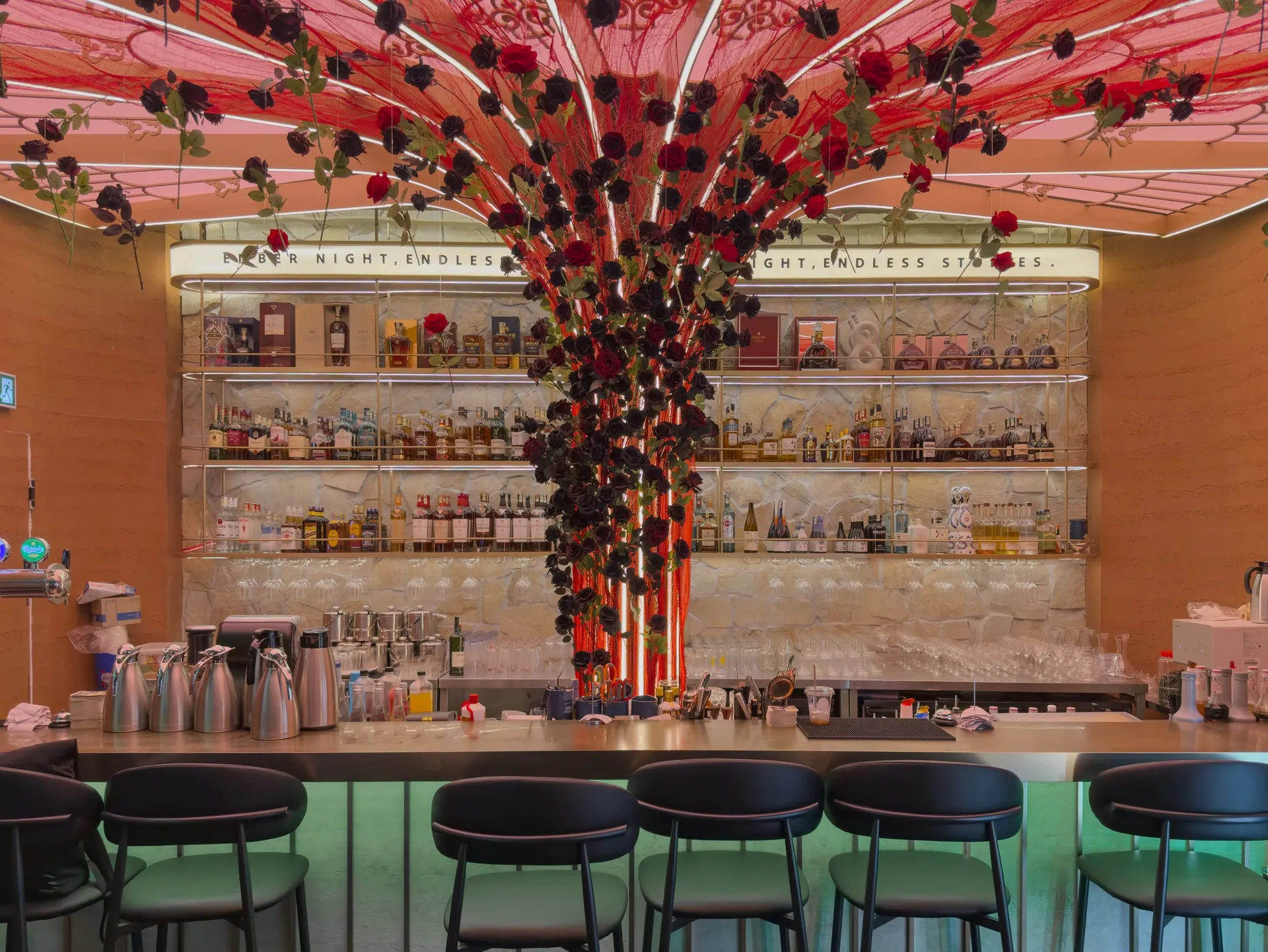 Bar counter beneath a red blossom installation